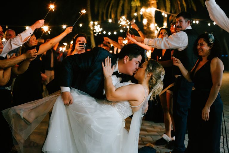 Newlywed couple kissing at a lively evening celebration